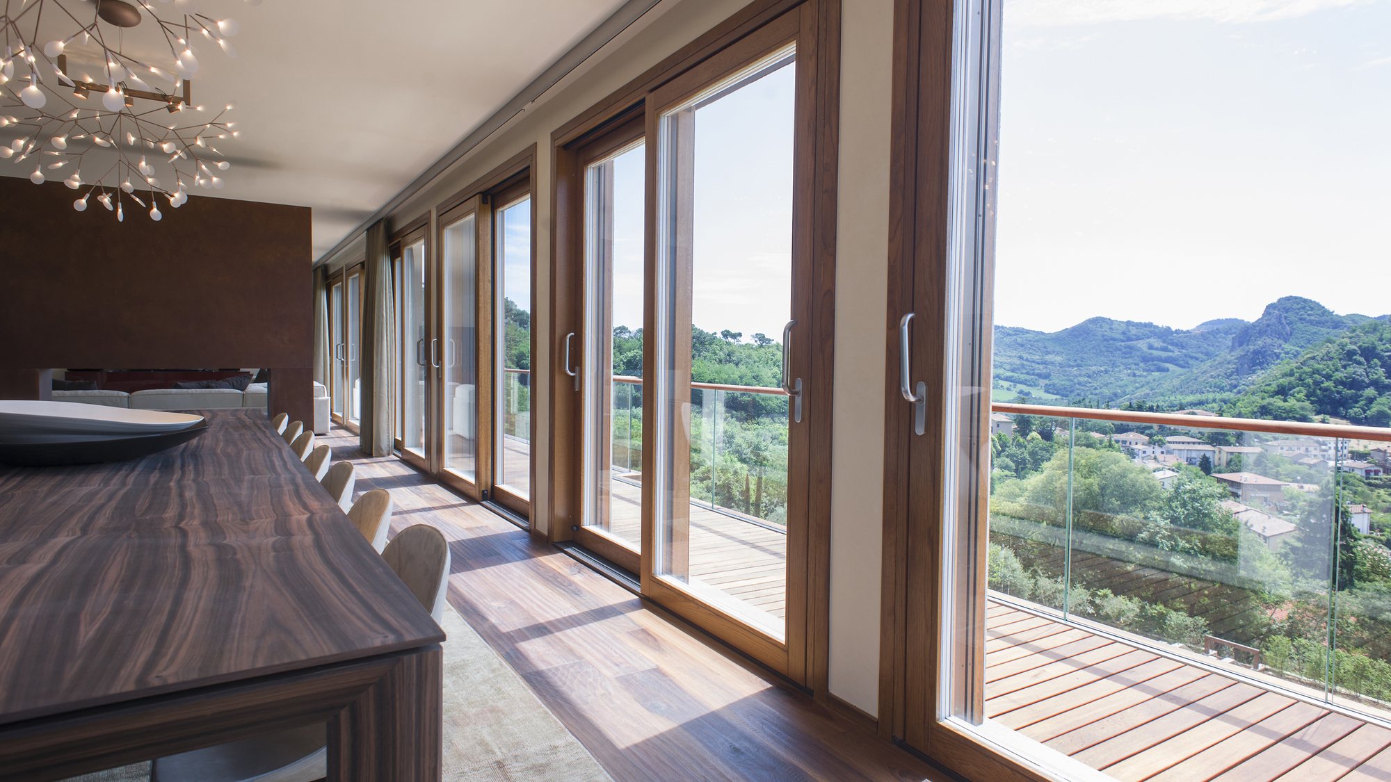Sala da pranzo con pavimento in rovere e ampie vetrate aperte sulla valle