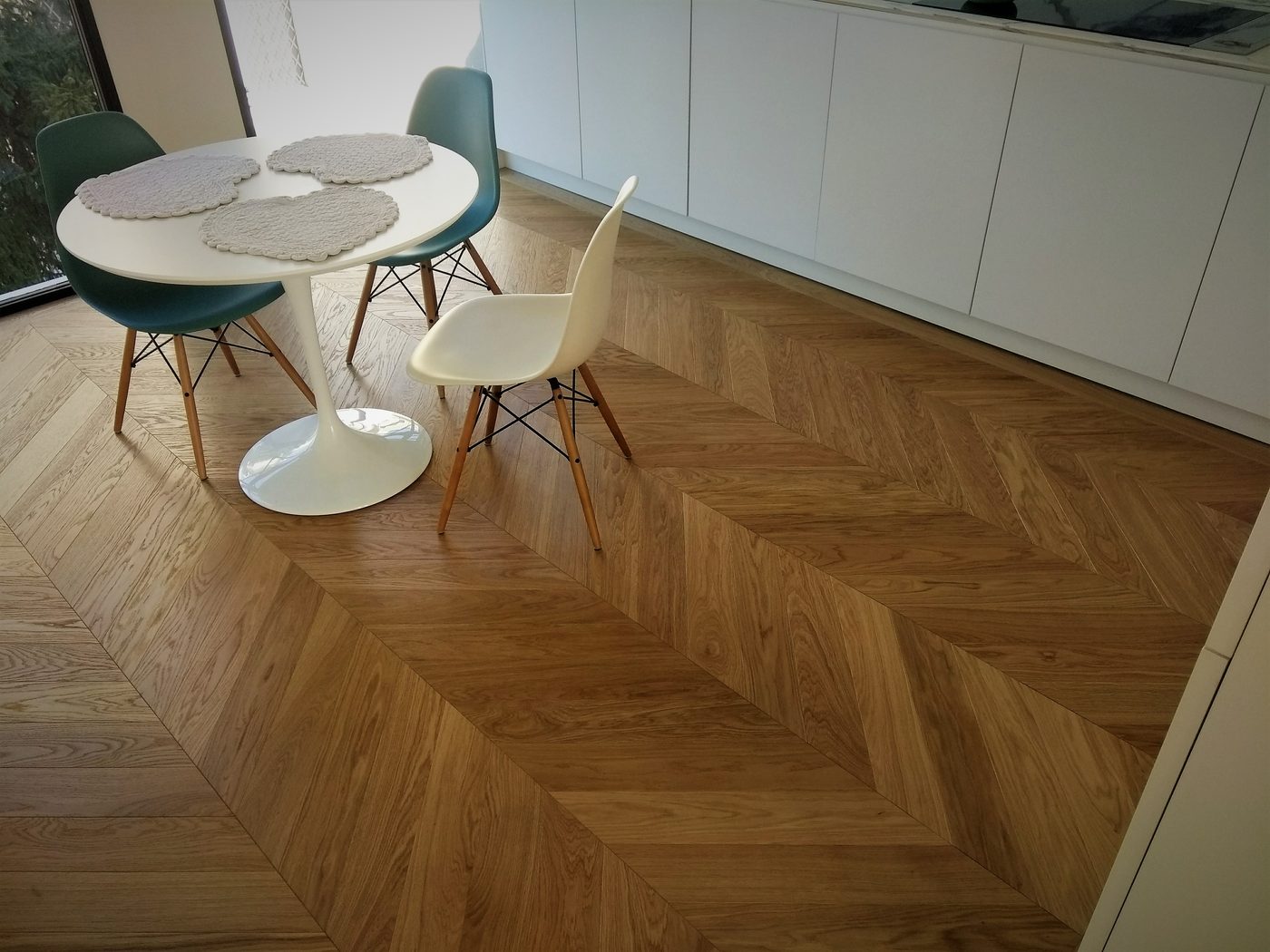 Pavimento in rovere posato a spina ungherese in una cucina, con tavolo tondo bianco