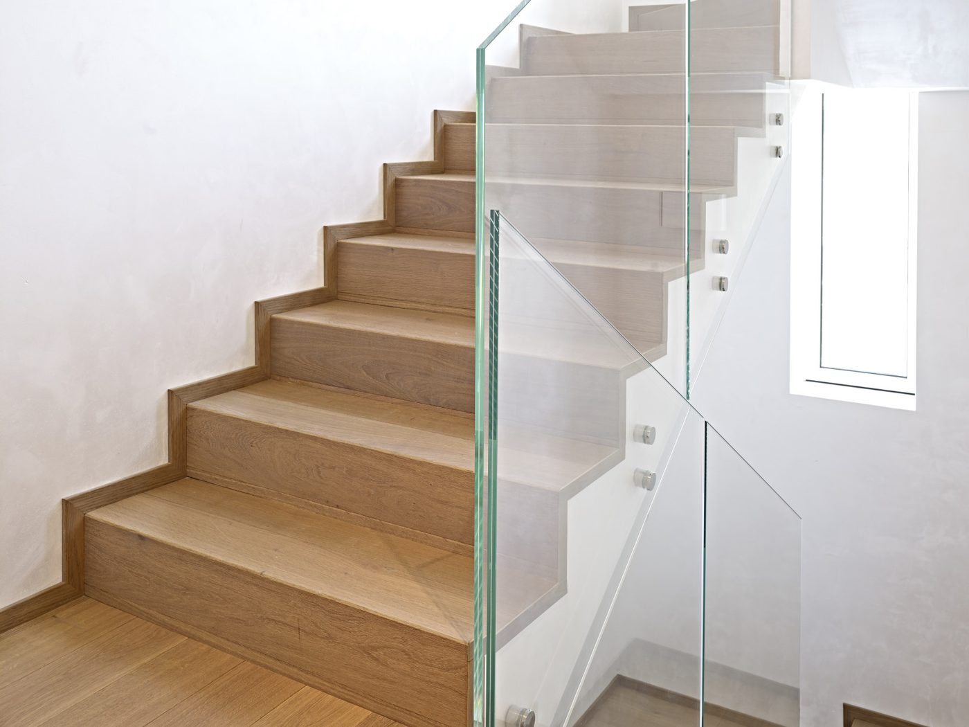 Scala interna con gradini in rovere chiaro e parapetto in vetro